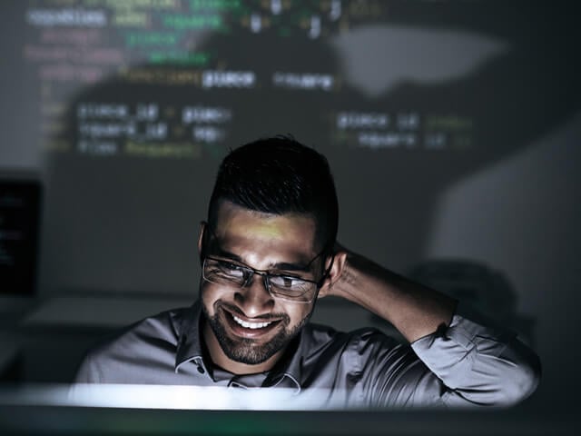 Man smiling at a screen with legacy application code projected behind him