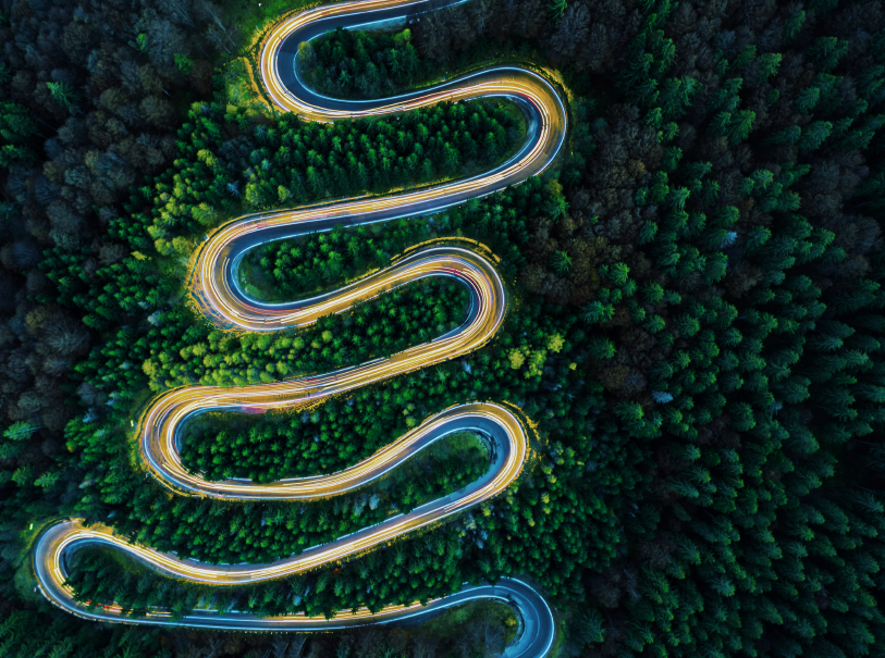 Aerial view of lights on a winding road through the forest in the evening
