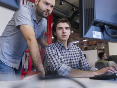 a desktop support analyst helps a worker at a computer