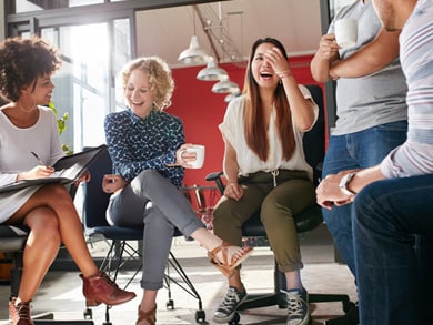group of diverse young professionals laugh in a circle