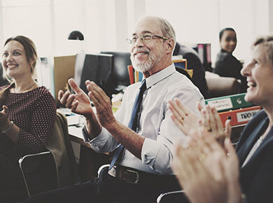 Employees sitting together and clapping at the recognition of their colleagues