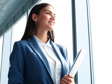 recent female grad in suit stands at window