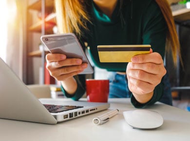 A woman looking at her credit card and phone