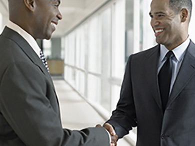 two professional men smiling and shaking hands