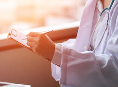 A doctor writing patient information on a clipboard