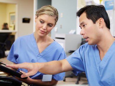healthcare professionals in scrubs review data on a tablet