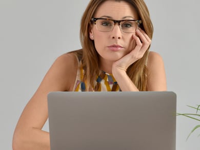 bored female with glasses sits at computer