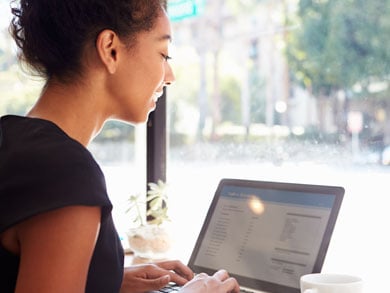 young female sits in coffee shop on laptop