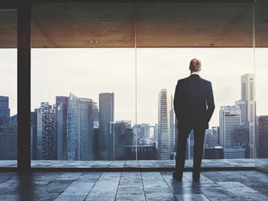 business man overlooking a city in an empty room