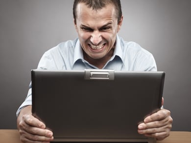 frustrated man grabs computer in anger
