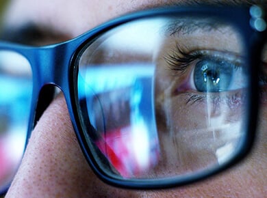 computer screen reflecting in the glasses of a professional monitoring for peak performance