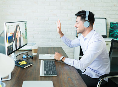 A man sits waving at his computer as he's onboarding in a virtual world
