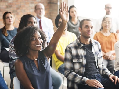 group of diverse employees raise hands during onboarding
