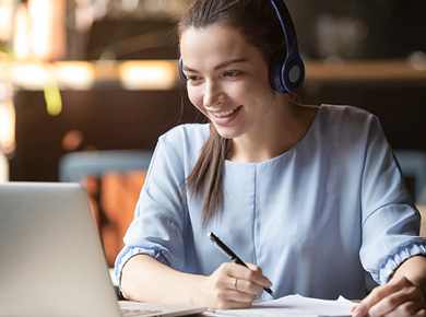 young white female professional completing a learning development program on a laptop using headphones