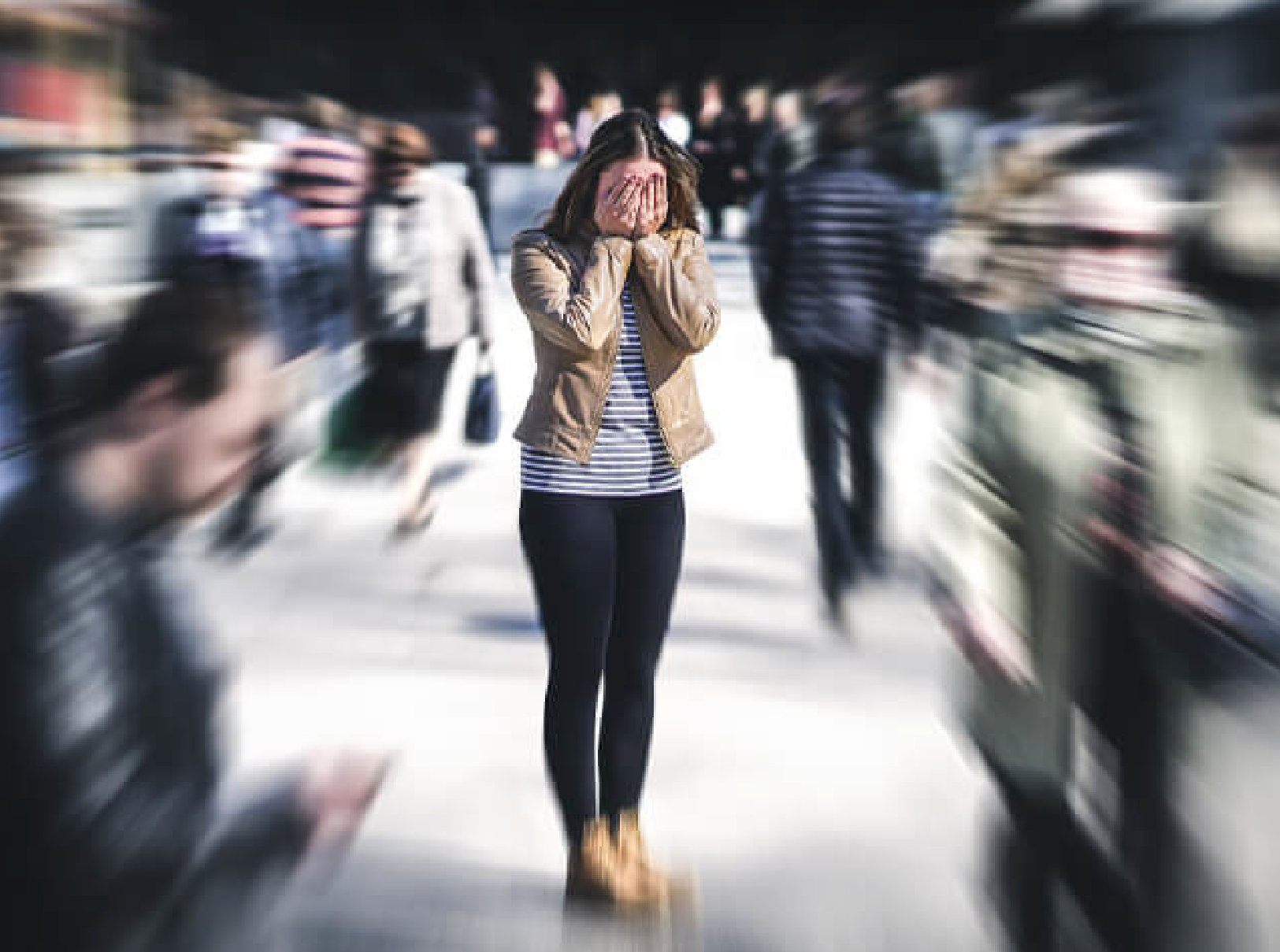 woman standing in the middle of a blurred out crowd face in palms