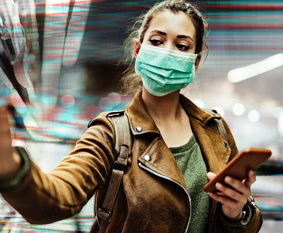 woman with medical mask on checking product data on her phone while reaching for an item