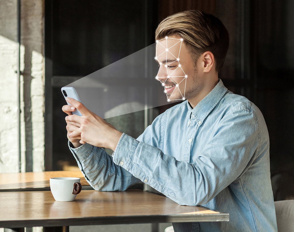 A man sits holding his phone as it scans him to determine how to personalize content for its target audience