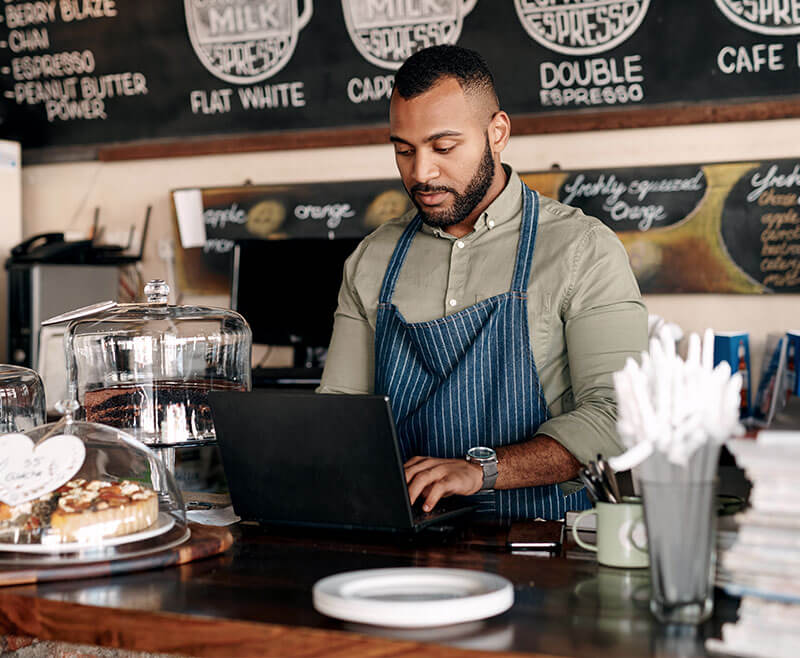coffee shop employee working at laptop register