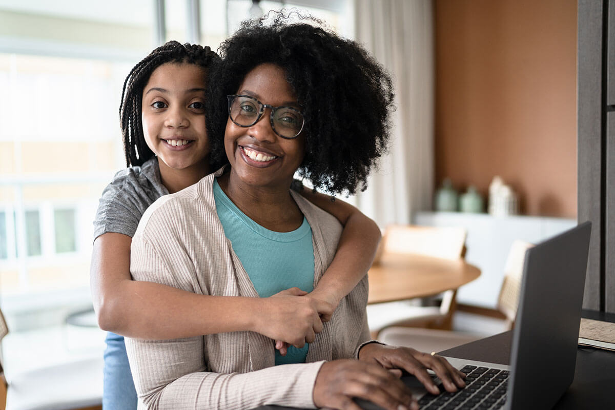 daughter hugging mother working from home