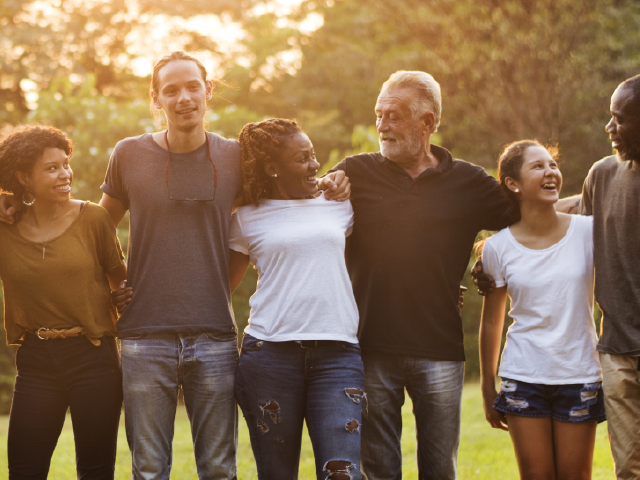 group of individuals laughing and smiling outside while embracing one another.