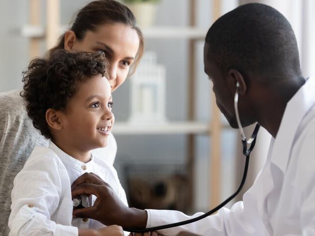 child recieving medical assistance from a healthcareworkerwhile being held by his mother