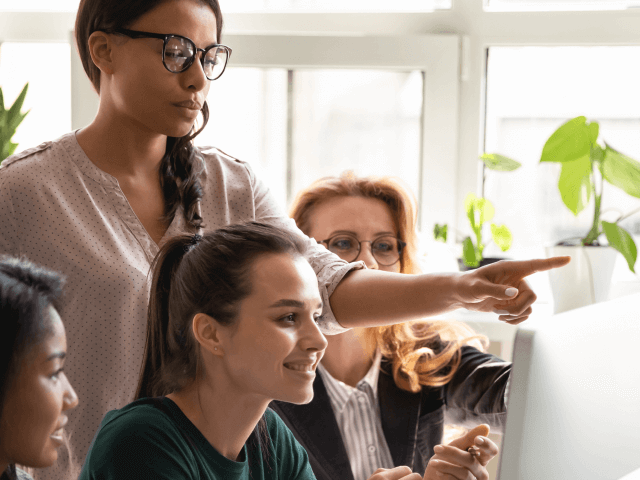Colleagues at a social media company collaborating around a computer.