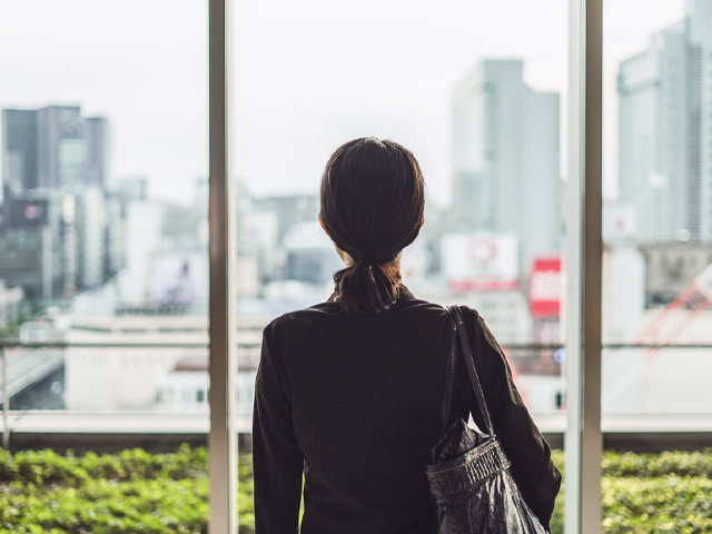 young female professional gazing out window while waiting for interview to begin
