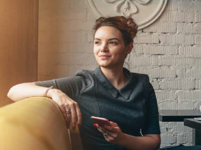 young white woman sitting on couch with phone in hand