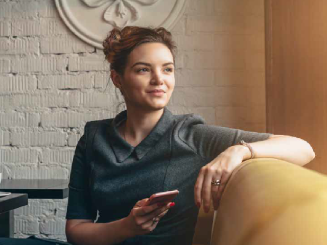 young white woman sitting on couch with phone in hand