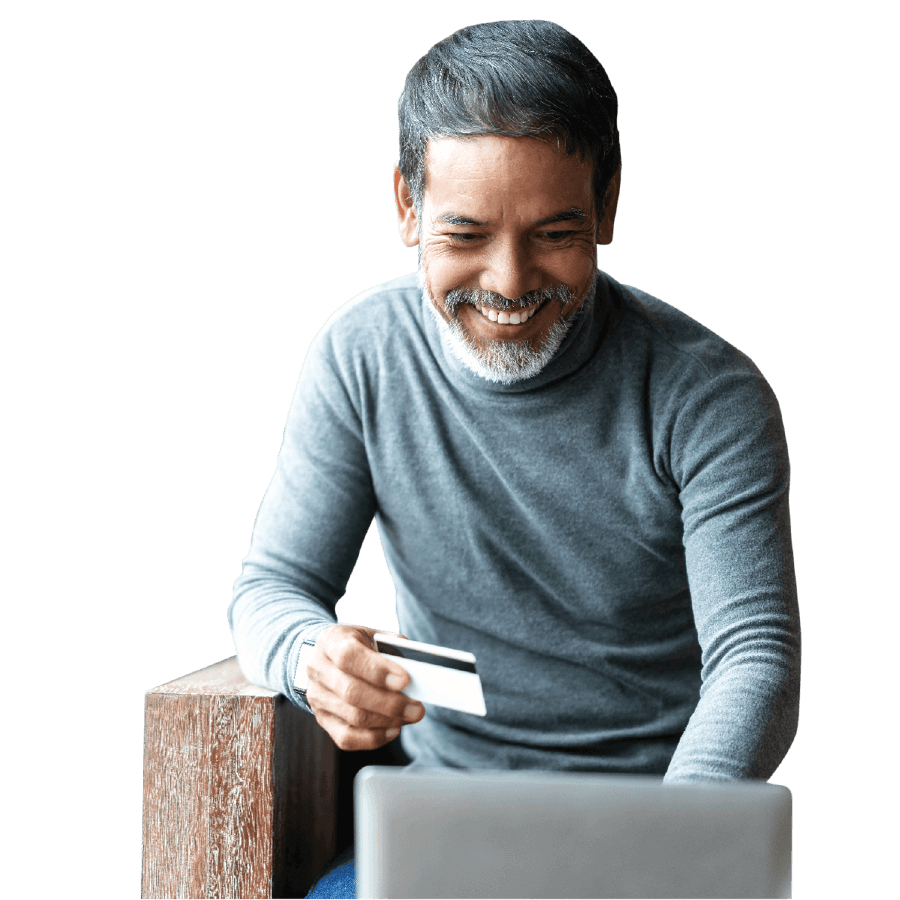 man seated in front of a laptop holding payment card.