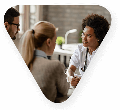 Phycians Assistance, or another heatlhcare profressional, speaking with two individuals seated across the table.