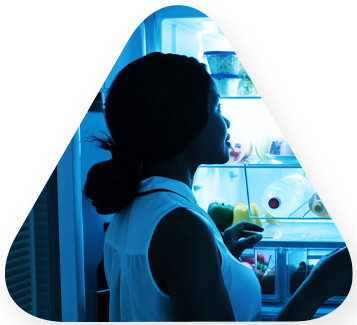 young woman in a dark kitchen with the fridge door opened