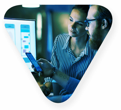 Two people comparing mobile enterprise applications interface mockups between computer monitors and a smartphone
